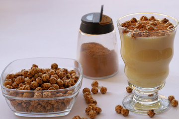 Boza in glass and lebelebi on it and cinnamon next to leblebi in bowl.