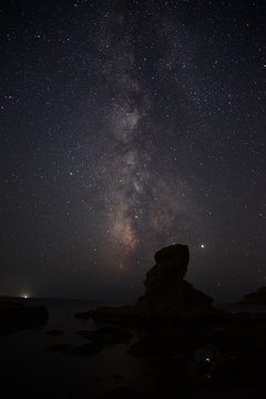 silhouette of stone man in front of the galaxy