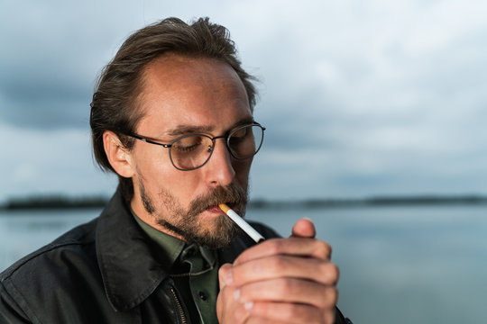 Young handsome man lighting up cigarette