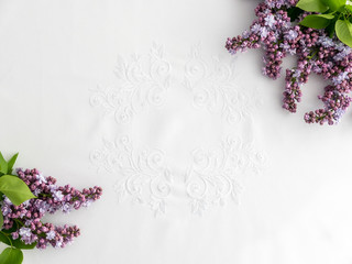 Bouquet of lilac on white ornamented tablecloth