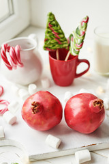 Christmas sweets pomegranate, milk, marshmallows, candies on a white background by the window