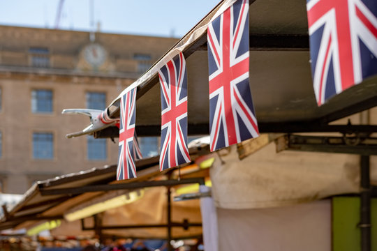 Shallow focus image of a Union Jack flack on a row on flag bunting, above a market stall. Part of a bank holiday celebration in the UK in early summer.