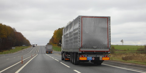 Truck drive on autumn country highway asphalt road, cargo transport logistics, wide , rear view