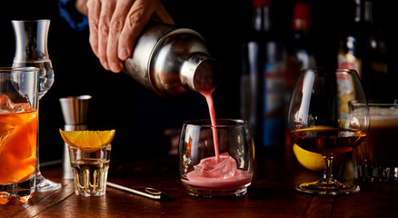 Bartender pouring a fruity cocktail from a shaker