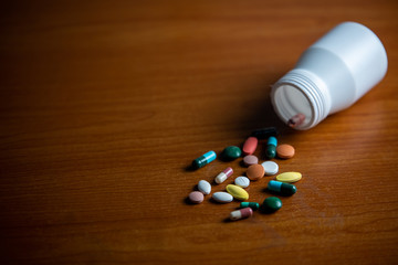 A bottle of pills and capsule .pour on the wooden table. Concept danger of pill overdose