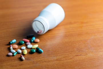 A bottle of pills and capsule .pour on the wooden table. Concept danger of pill overdose