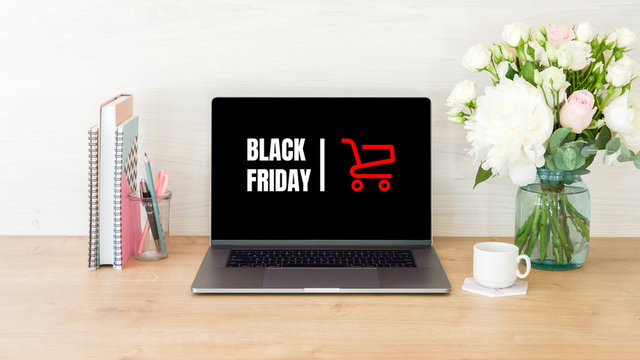 Black Friday concept. Laptop screen with text sign "Black Friday" and shopping cart on women workplace