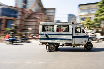 Motor rickshaw is riding fast with passengers through Kathmandu streets.
