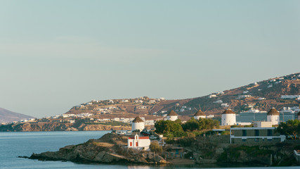 View of white buildings and famous windmills on sea shore in mykonos