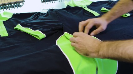 Male worker checking the sewing on cotton t-shirts
