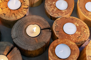 Burning candles in wooden candlesticks. Bright warm glow from candle flames.