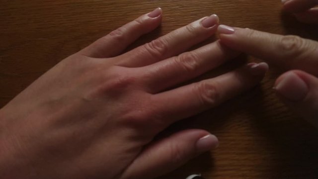 Rubbing almond hand oil vinto cuticles close up. Skin Care products procedure. Beautiful and well-groomed hands of a woman with a pink manicure.