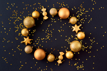 Flat lay frame with gold christmas balls and golden confetti on a dark background