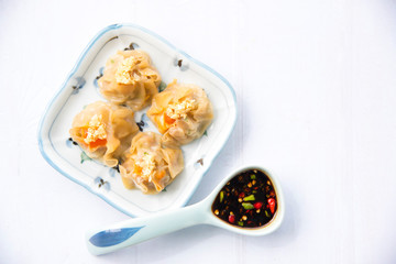 Cantonese Dimsum food cuisine . Fresh  prawn wrapped in yellow dumplings, Steamed Chinese wrapped in yellow Dumplings.White wood flooring  background, space.Chinese popular dim sum food.
