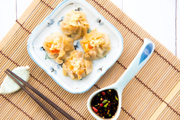 Cantonese Dimsum food cuisine . Fresh  prawn wrapped in yellow dumplings, Steamed Chinese wrapped in yellow Dumplings.White wood flooring  background, space.Chinese popular dim sum food.