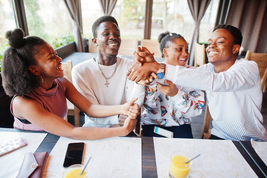 Happy african friends sitting and chatting in cafe. Group of black peoples meeting and play games by hands in restaurant.