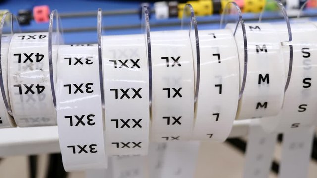 Close-up of several size tag tapes from Small to Extra five large size clothes proportions rolls. Important supply for marking clothes in a clothing store