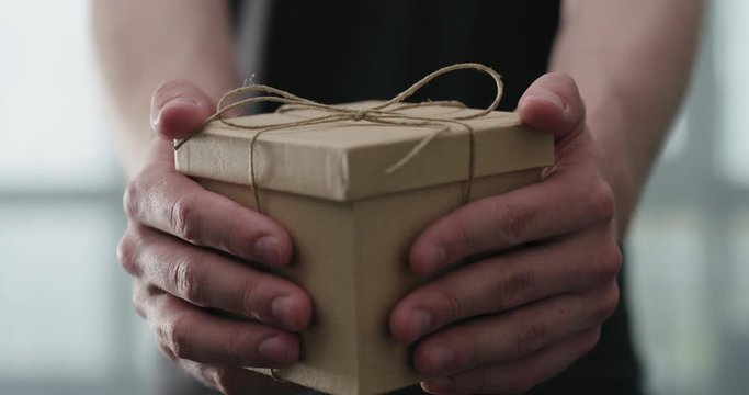 Slow motion young man shows brown craft paper gift box