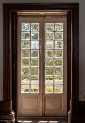 Wooden carved and glazed doors leading from old house into garden with sunlight
