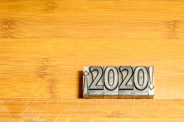 Happy New Year 2020 on wooden background with types of press between exclamation marks