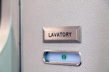 Vacant green sign, vacant symbol on an airplane lavatory door. Raised, brushed metal lavatory sign, recessed plastic vacant sign. Toilet room, wc, closet on airplane board