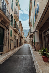 An alley surrounded by old houses, with an old bicycle, and plants in the picturesque village of Soller, Mallorca, Spain. Vertical photo.