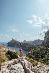 Epic shot of a man hiking on the edge of a rock contemplating the incredible view of Cape Formentor in Majorca, Balearic Islands, Spain. Vertical photo. © Fabian