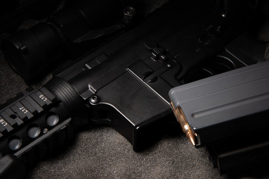 dark assault rifle on dark grey foam with brass bullet in magazine ammo ready to fire stock photo