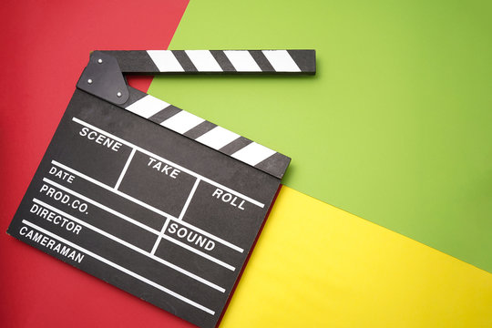 Filmmaker profession. Clapperboard on multiples color background top view copyspace