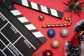 Filmmaker clapperboard with christmas decorations on red background. A Christmas movies and holiday...