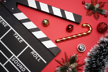 Filmmaker clapperboard with christmas decorations on red background. A Christmas movies and holiday...