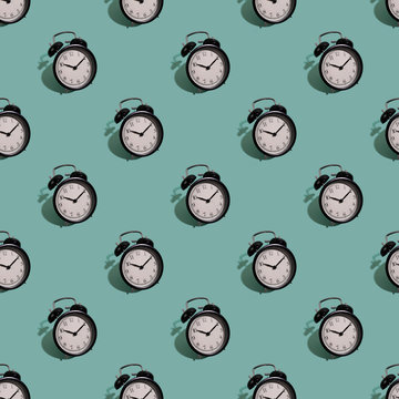 Many black classic style alarm clock with hard shadow isolated on green background. Smile time concept. Seamless pattern