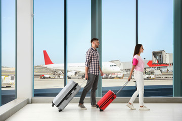 Young couple with suitcases in airport terminal