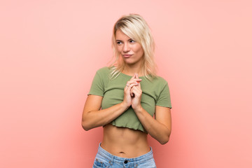 Young blonde woman over isolated pink background scheming something