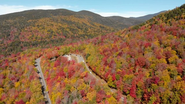 Aerial drone view of colorful fall foliage leaves over a mountain road in the New England state of New Hampshire.