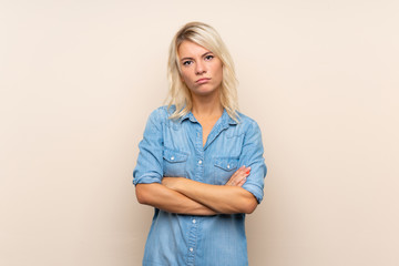 Young blonde woman over isolated background keeping arms crossed