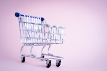 empty shopping cart over light pink background