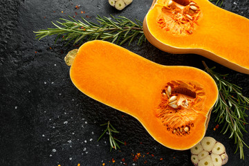 Fresh Butternut squash with rosemary, garlic, chilli flake and salt on black rustic background