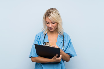 Young blonde woman over isolated background with doctor gown and writing in a folder