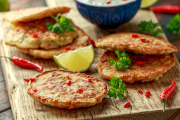 Corn fritters, pancake with dip white sauce, lime and chilli on wooden board