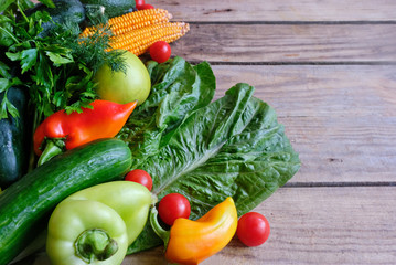 Assortment of fresh vegetables (peppers, cherry tomatoes, avocado, spinach, parsley, lettuce, corn) on a gray wooden background. Top view, copy space. Elements of vegan and keto diets.  Detox, cleansi