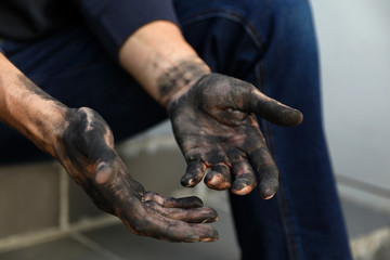 Dirty worker sitting on stairs, closeup of hands