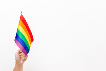 A hand holding an lgbt rainbow flag as a symbol of tolerance and protection of gay rights, white background, copy space