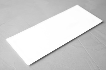 Blank palm card on light grey stone background, closeup. Mock up for design