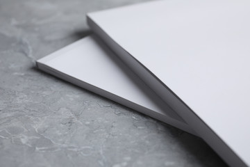 Blank books on light grey marble background, closeup. Mock up for design