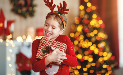 happy laughing child girl with christmas present at home.