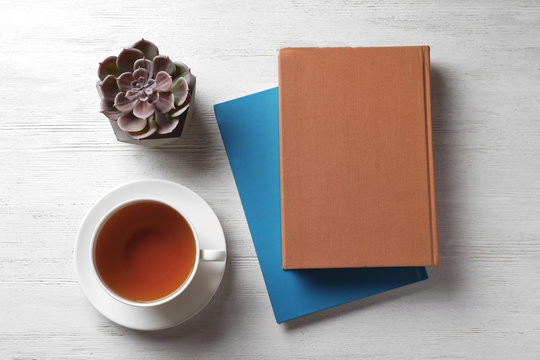 Flat Lay Composition With Hardcover Book And Cup Of Tea On White Wooden Table