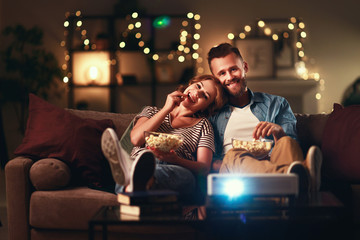 Family couple watching television projector at home on sofa.
