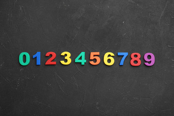 Colorful magnetic numbers on black stone background, flat lay