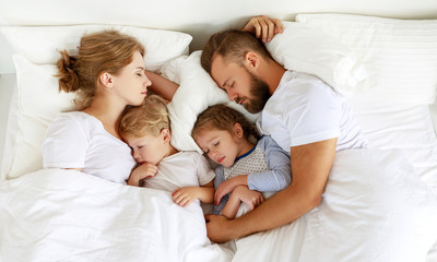 healthy sleep. happy family parents and children sleeping in white bed - Powered by Adobe